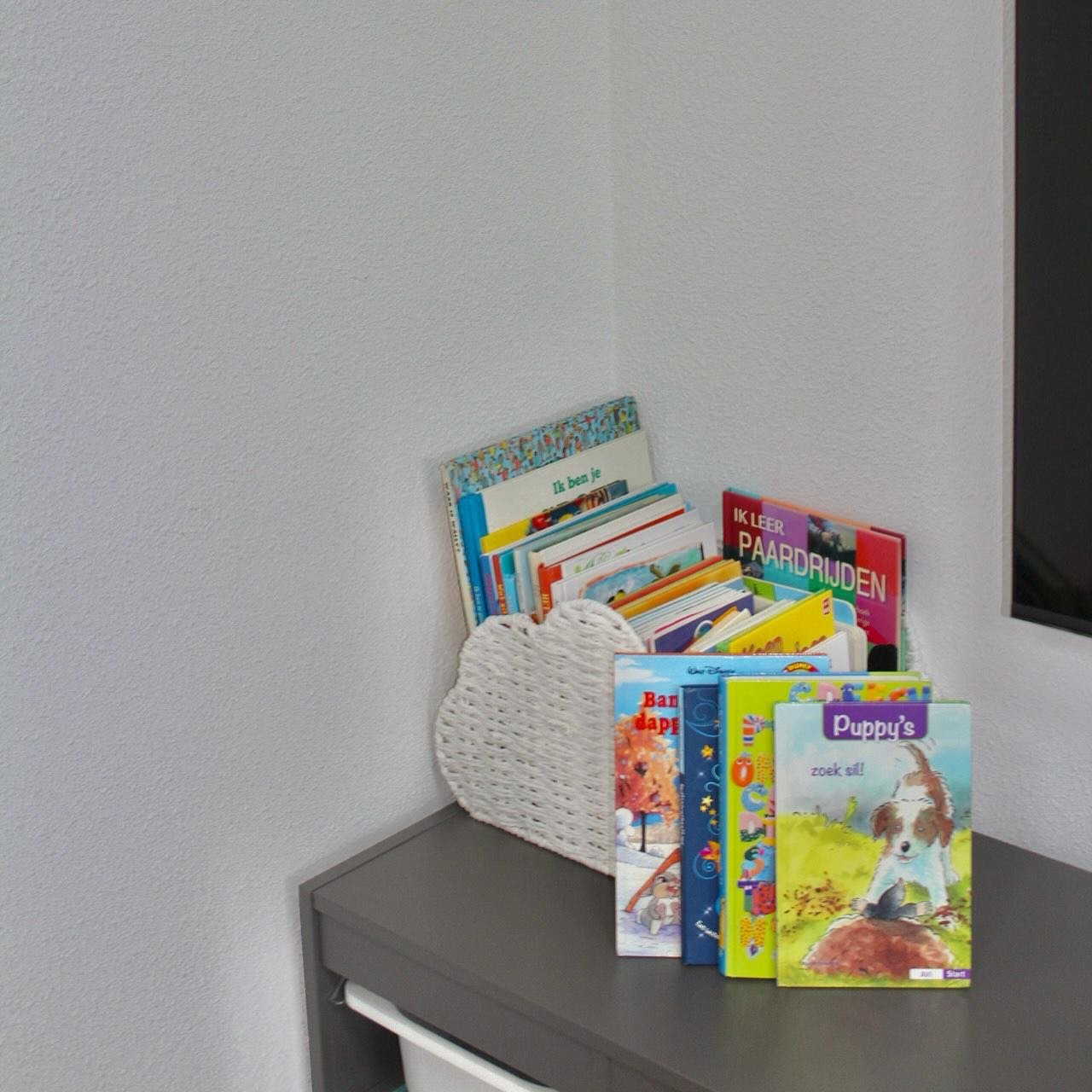 Een mand met voorleesboeken op een kast in de leeshoek.